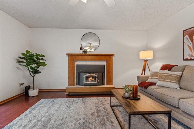 living room with a textured ceiling, a fireplace, dark hardwood / wood-style flooring, and ceiling fan