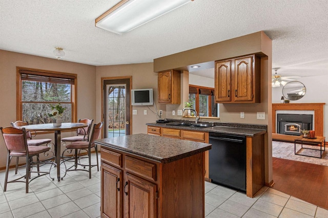 kitchen featuring dishwasher, a textured ceiling, sink, a kitchen island, and light wood-type flooring