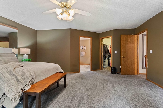 bedroom featuring ceiling fan, a closet, a walk in closet, and carpet