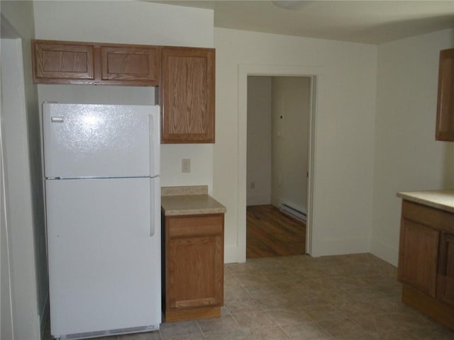 732 Chippewa St, Eau Claire, WI 54703 - kitchen with freestanding refrigerator, baseboard heating, brown cabinets, light countertops, and light tile patterned flooring