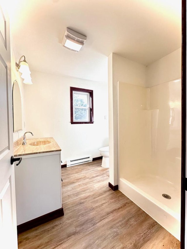 bathroom featuring hardwood / wood-style floors, vanity, a shower, a baseboard radiator, and toilet