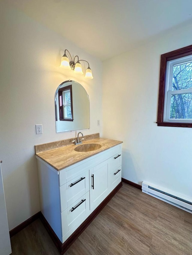 bathroom with hardwood / wood-style flooring, baseboard heating, and vanity