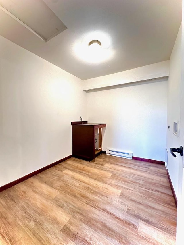 spare room with baseboard heating and light hardwood / wood-style flooring