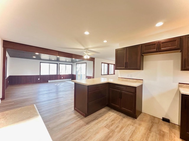 kitchen with dark brown cabinets, light wood-type flooring, kitchen peninsula, and ceiling fan