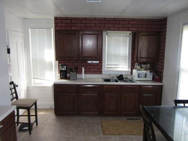 kitchen with decorative backsplash, a paneled ceiling, sink, and light tile patterned floors