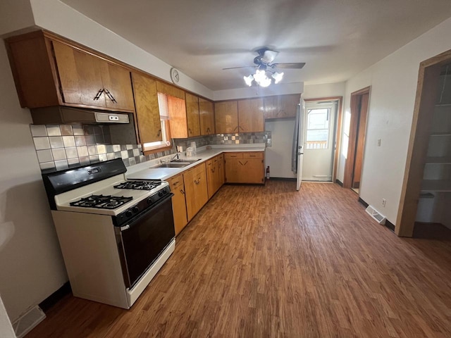 kitchen with hardwood / wood-style floors, tasteful backsplash, gas range gas stove, and ceiling fan