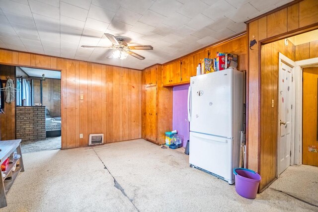 kitchen with light carpet, wooden walls, white fridge, and ceiling fan