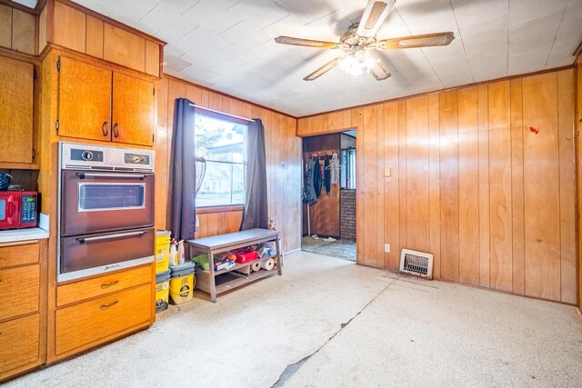 kitchen featuring oven, wood walls, light colored carpet, and ceiling fan