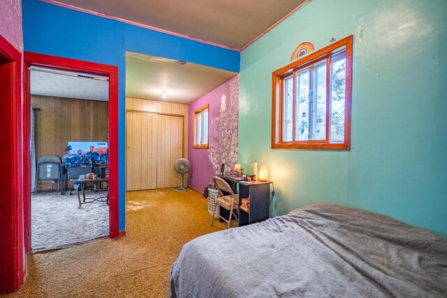 carpeted bedroom with wood walls, a closet, and crown molding