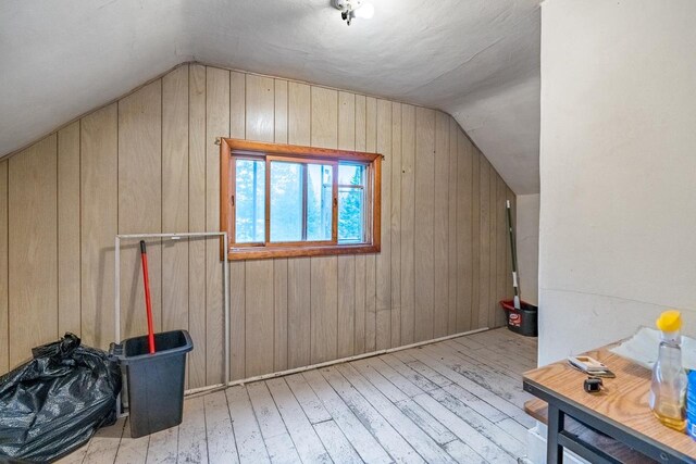 bonus room featuring light hardwood / wood-style flooring, vaulted ceiling, and wooden walls