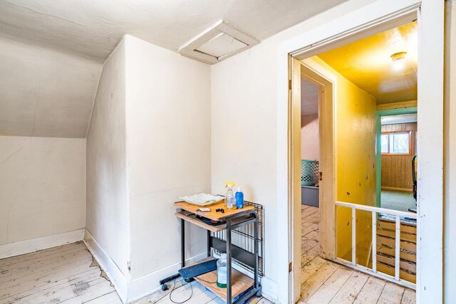 hallway with light hardwood / wood-style floors and vaulted ceiling