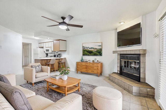 tiled living room with sink, ceiling fan, and a fireplace