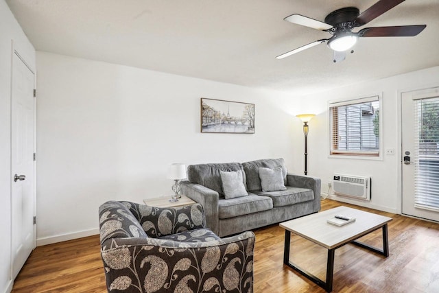 living room featuring hardwood / wood-style flooring, ceiling fan, and an AC wall unit