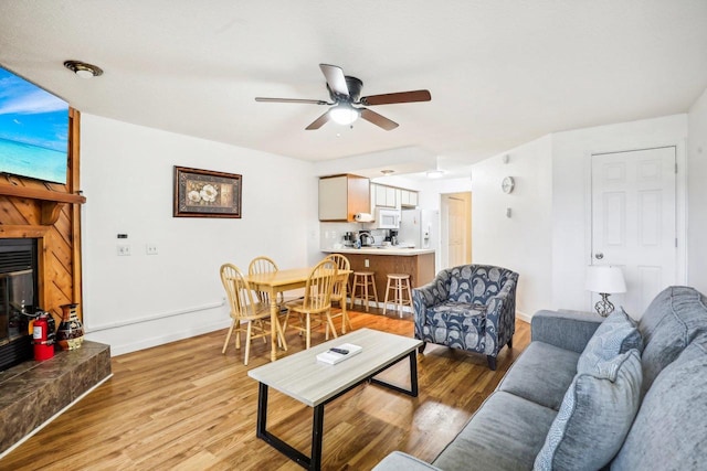 living room with light hardwood / wood-style floors, ceiling fan, and a tile fireplace