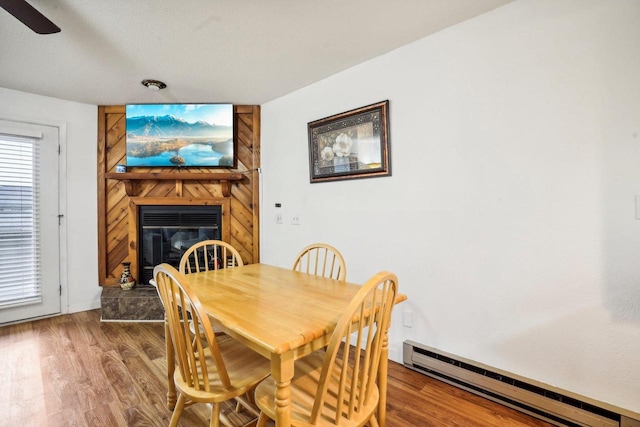 dining area featuring a textured ceiling, wood-type flooring, and a baseboard radiator