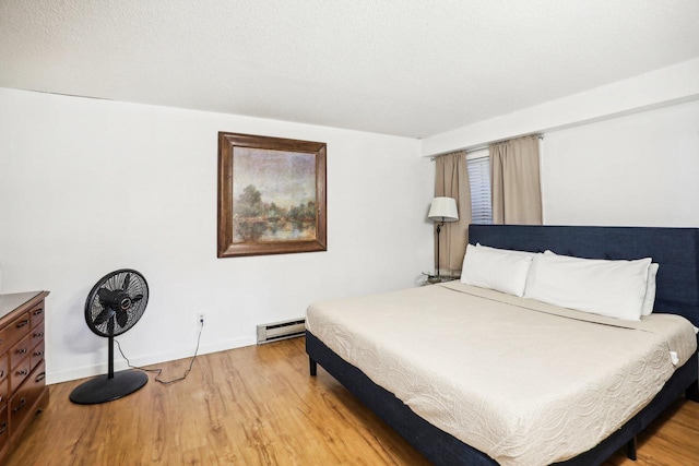 bedroom with a baseboard radiator, light hardwood / wood-style flooring, and a textured ceiling