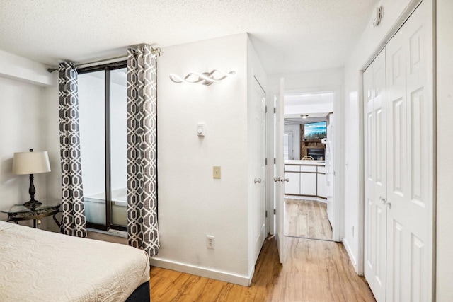 bedroom with wood-type flooring, a textured ceiling, a closet, and access to exterior