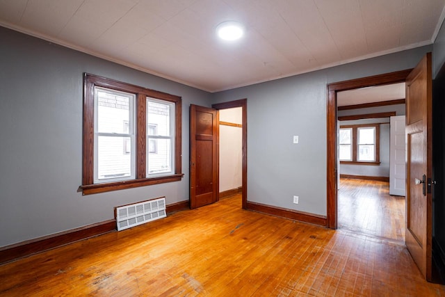 unfurnished bedroom with multiple windows, wood-type flooring, and ornamental molding