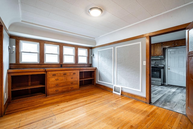 unfurnished office with light wood-type flooring, plenty of natural light, and built in desk