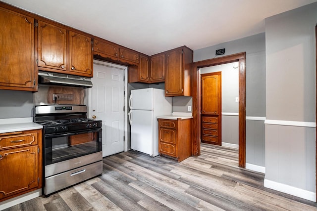 kitchen with stainless steel range with gas stovetop, white fridge, and light hardwood / wood-style flooring