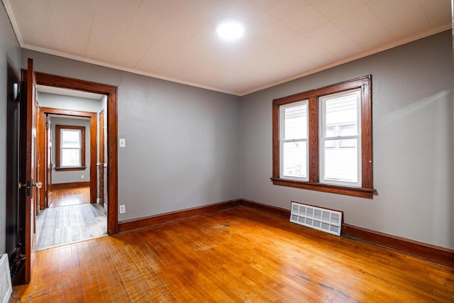 empty room featuring ornamental molding and hardwood / wood-style flooring