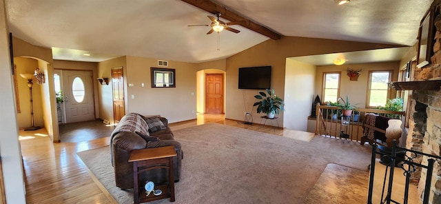 living room featuring a fireplace, ceiling fan, vaulted ceiling with beams, and light hardwood / wood-style flooring