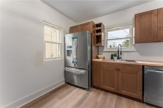 kitchen with light wood-type flooring, stainless steel appliances, and sink