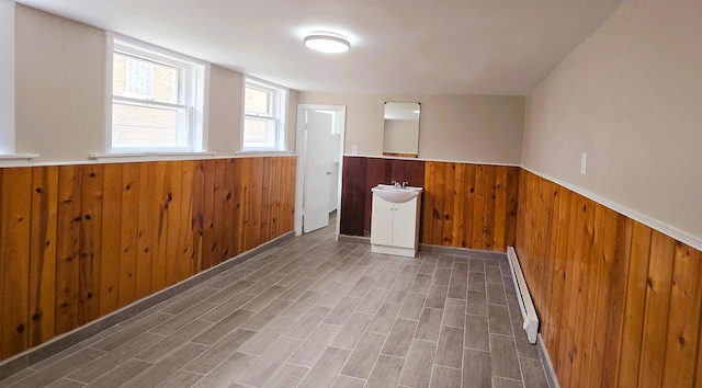 unfurnished room with dark hardwood / wood-style floors, wood walls, sink, and a baseboard radiator