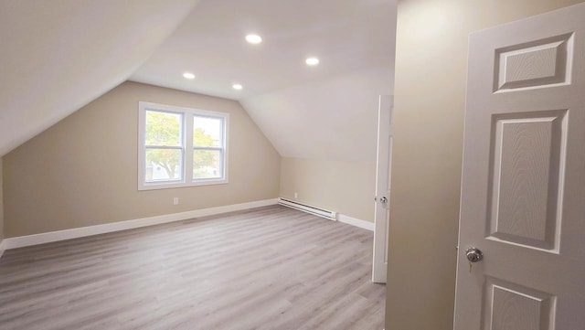 additional living space with a baseboard radiator, light hardwood / wood-style floors, and vaulted ceiling