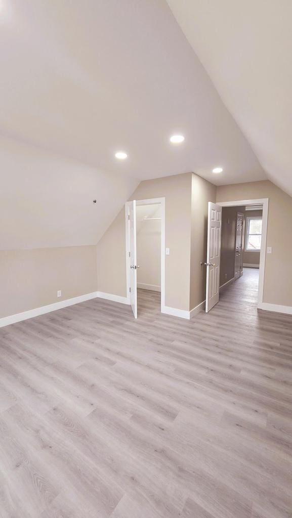 bonus room with lofted ceiling and light wood-type flooring