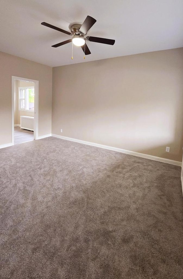 unfurnished room featuring ceiling fan and dark carpet