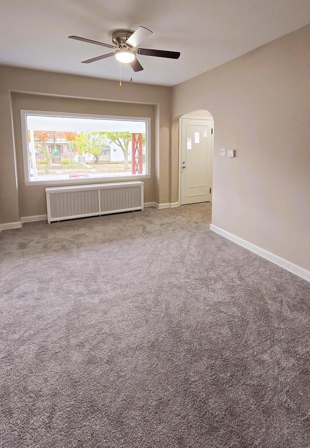 empty room with carpet, radiator, and ceiling fan