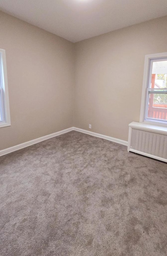 carpeted empty room featuring radiator heating unit