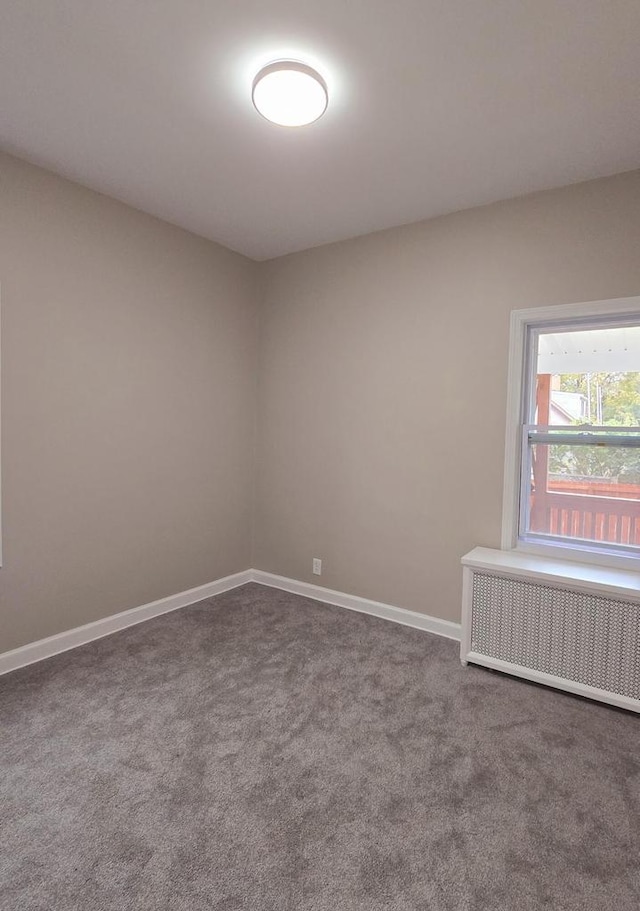 unfurnished room with radiator heating unit and carpet floors