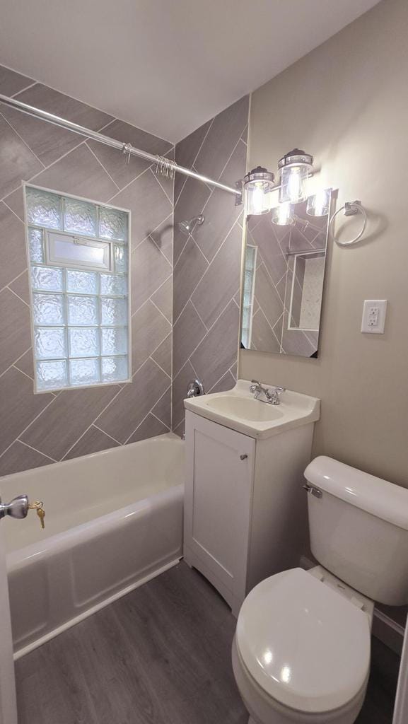 full bathroom featuring hardwood / wood-style flooring, vanity, toilet, and tiled shower / bath