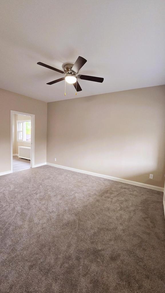 spare room with dark carpet and ceiling fan