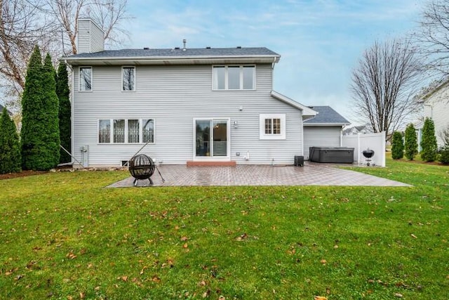 back of house with a lawn, a patio, and a hot tub