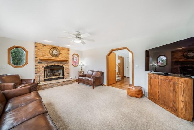 carpeted living room with ceiling fan and a brick fireplace