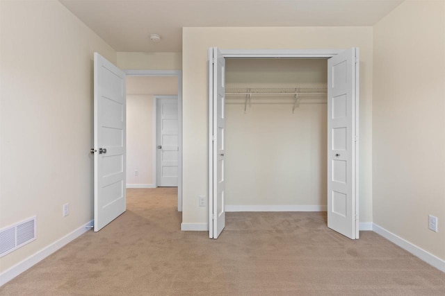 unfurnished bedroom featuring light carpet and a closet