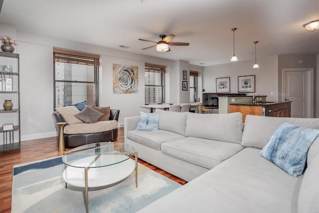 living room featuring ceiling fan, sink, a healthy amount of sunlight, and light wood-type flooring