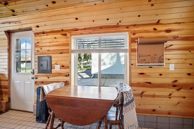 dining area featuring electric panel, wood walls, and light tile patterned floors