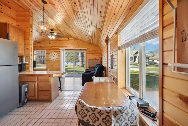 tiled dining area with lofted ceiling, wooden walls, ceiling fan, and wooden ceiling