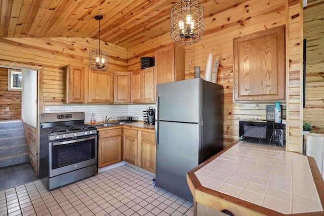 kitchen featuring stainless steel appliances, wood walls, pendant lighting, and vaulted ceiling