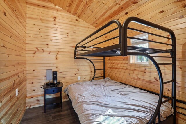 unfurnished bedroom with wood walls, dark wood-type flooring, and vaulted ceiling