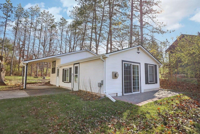 rear view of property featuring a patio, a lawn, and a carport