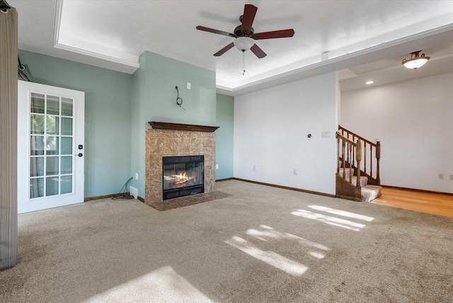 unfurnished living room featuring a tray ceiling, carpet flooring, and ceiling fan