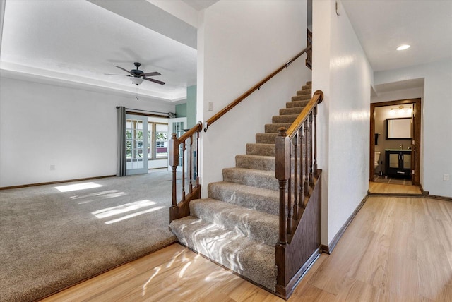 stairs featuring wood-type flooring and ceiling fan