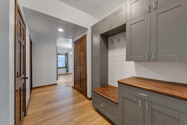 mudroom with a textured ceiling and light hardwood / wood-style floors