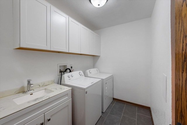 washroom with dark tile patterned flooring, washing machine and dryer, cabinets, and sink