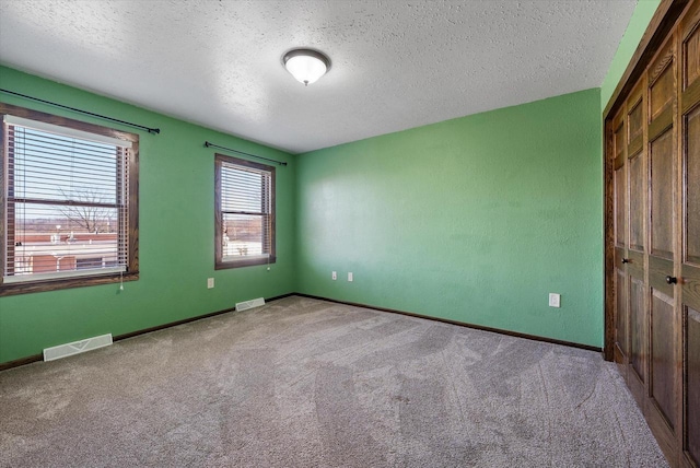 spare room featuring light carpet and a textured ceiling